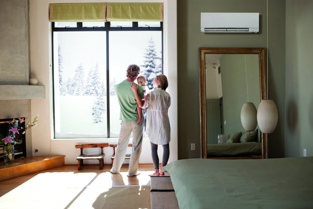 Family of three looking out a window at snow