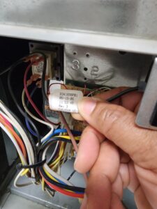 Technician holding a label against HVAC unit wiring