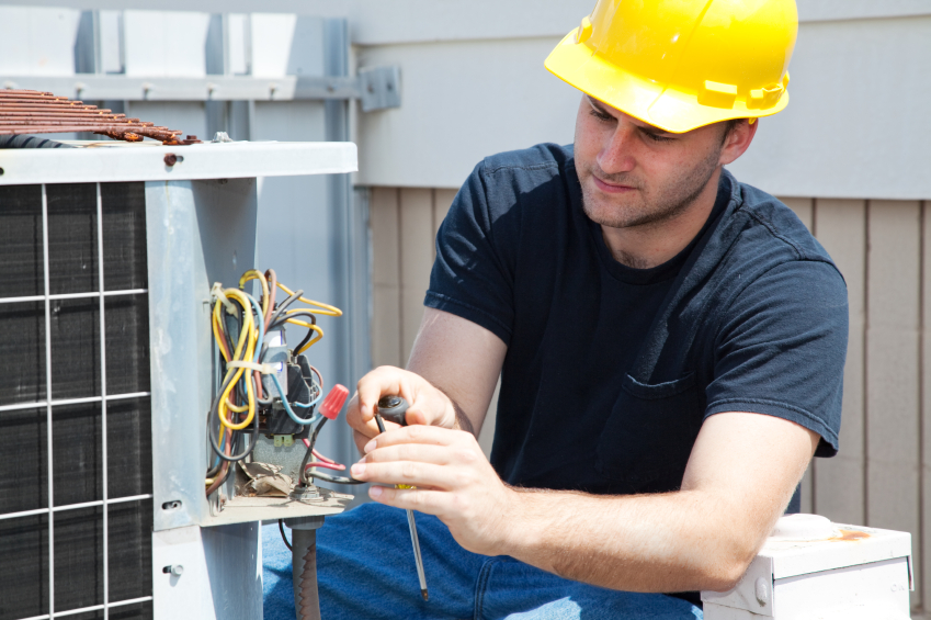 HVAC repairman fixing an air conditioning compressor.