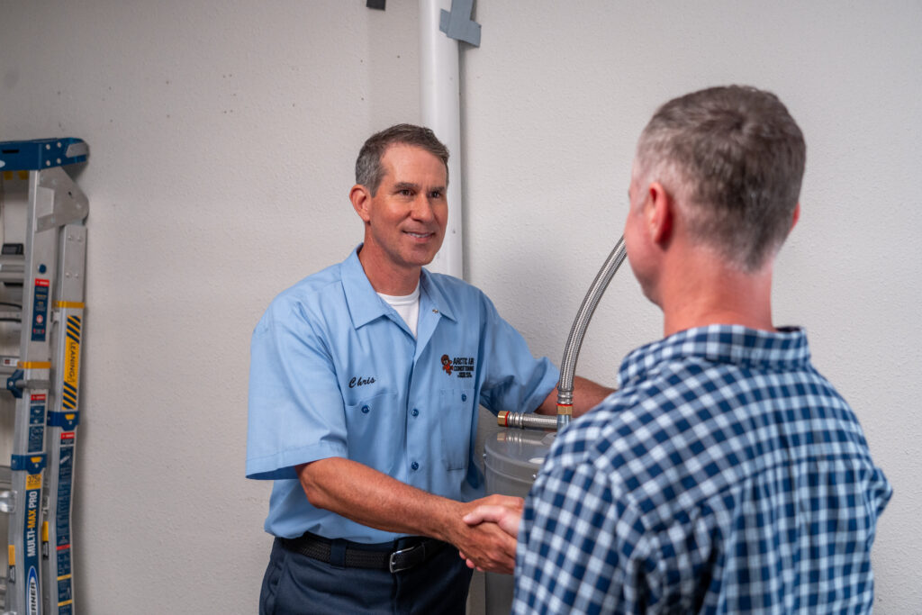 Local Plumber standing next to water heater with Customer