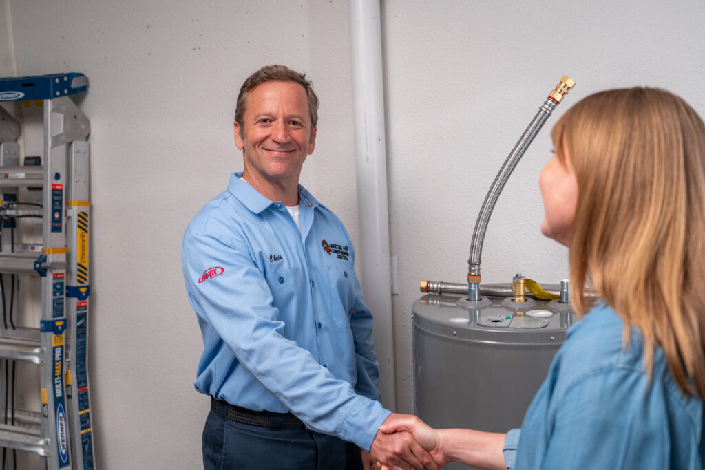 Smiling Arctic Air Plumber with Customer by Water Heater