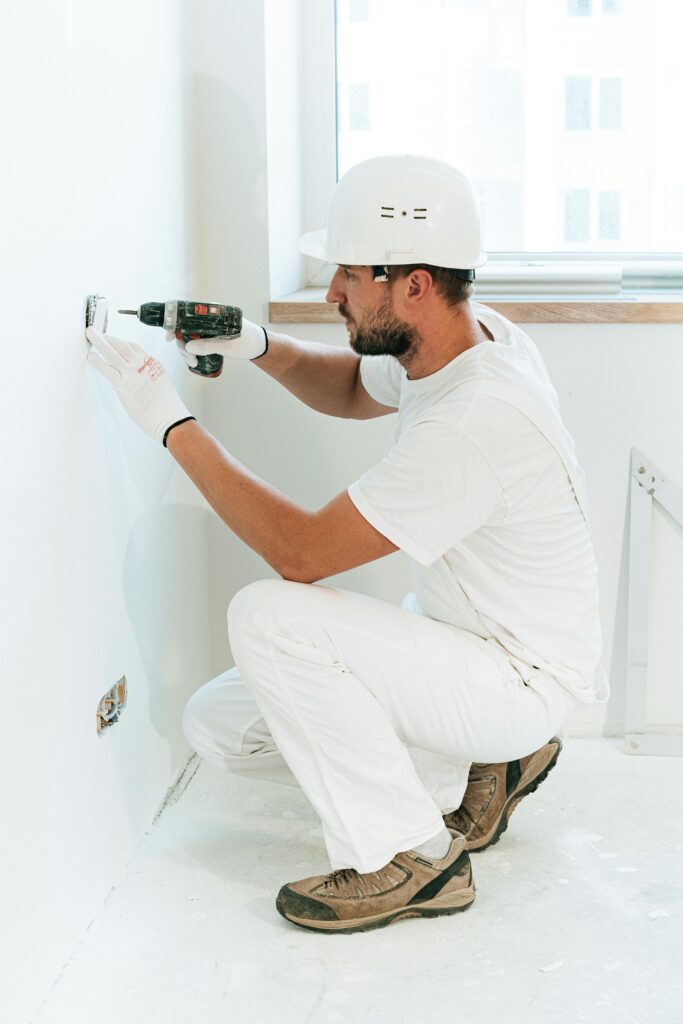 Electrician installing outlets in white room